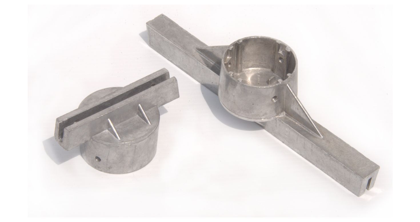 Two metal pieces are sitting next to each other on a white surface.