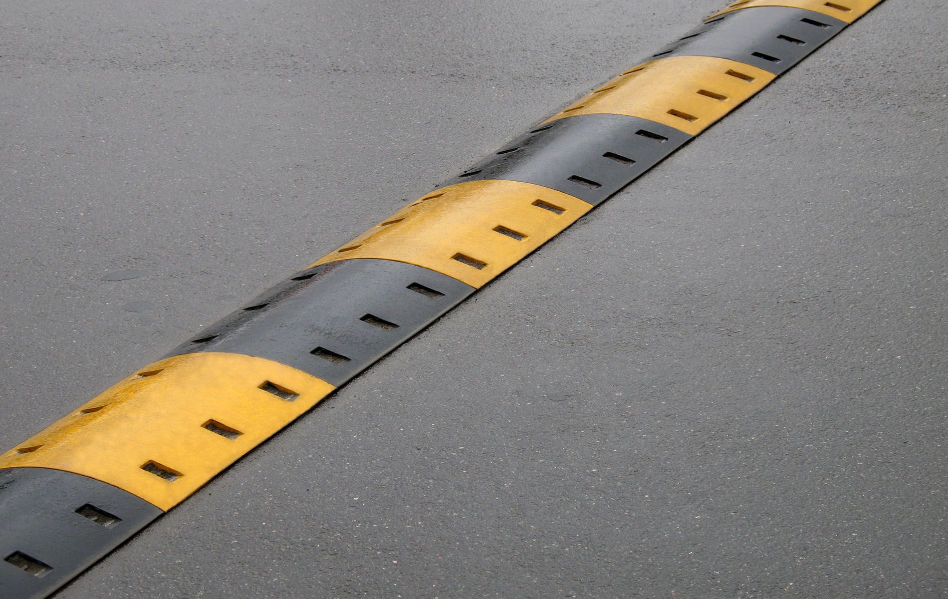 A yellow and black speed bump on the side of a road