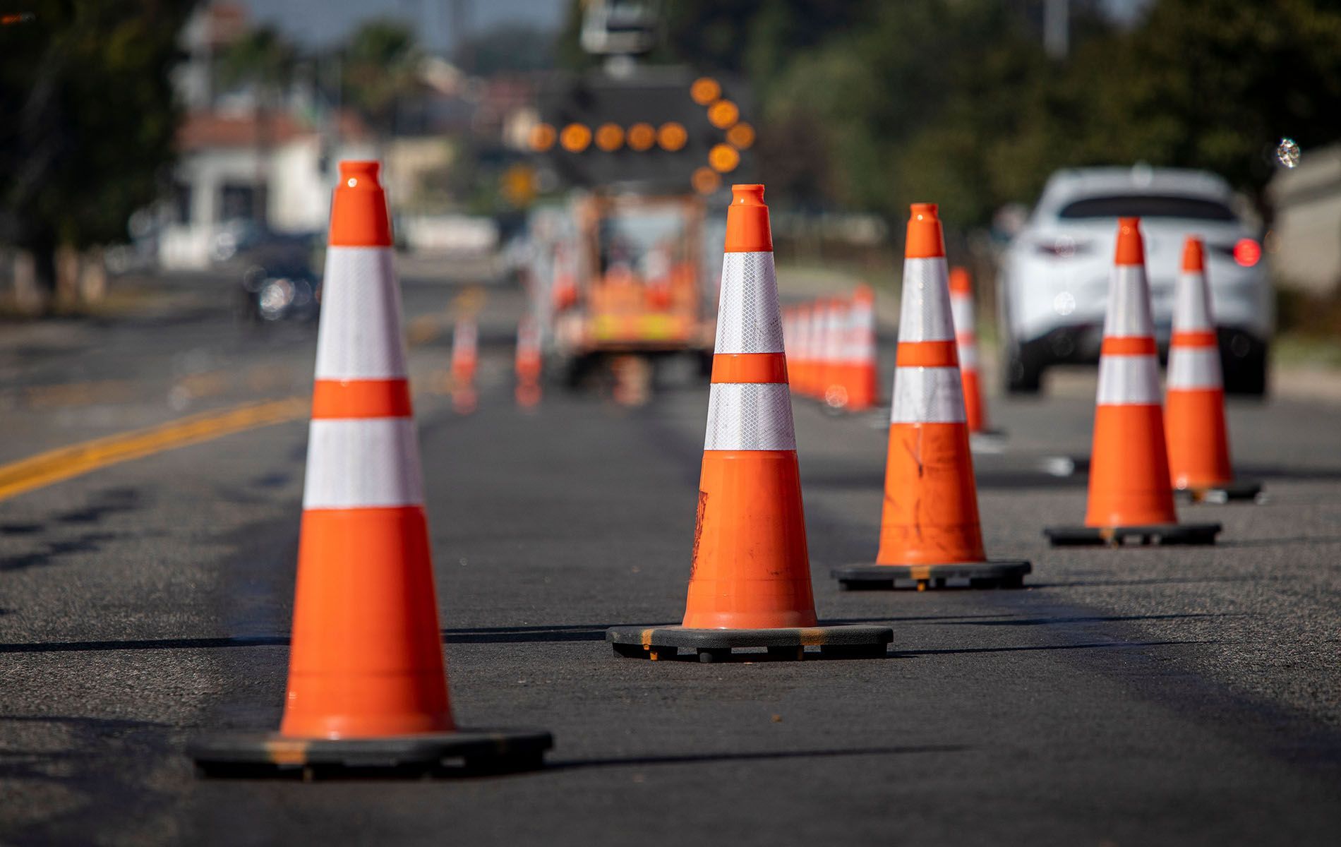 A row of orange and white traffic cones on the side of a road.