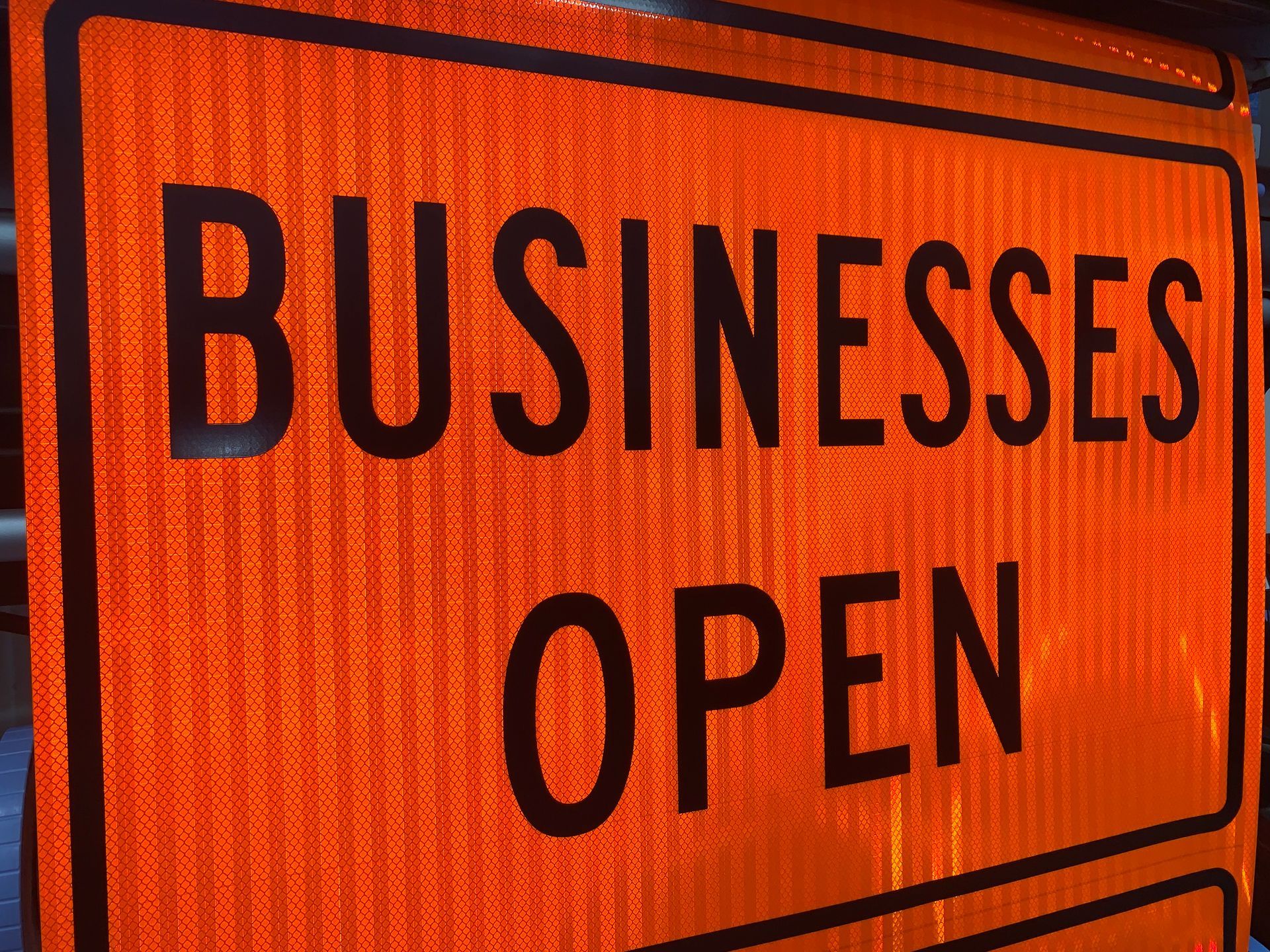 An orange sign that says businesses open on it
