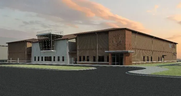 Large modern brick building at dusk with a central entrance and curved paved drive
