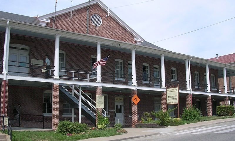 Two-story brick building with white porch railings and exterior stairs along a street