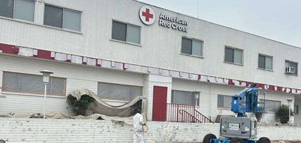 A man is standing in front of a building with a red cross on it.