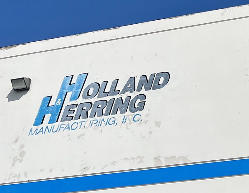 A close up of a Holland Herring manufacturing sign. (Before)