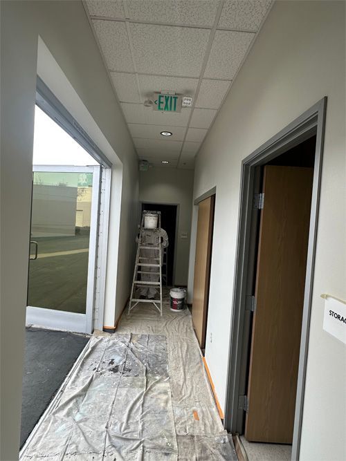 A hallway with a green exit sign on the ceiling.