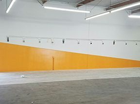 A large empty room with orange and white walls and lights hanging from the ceiling.