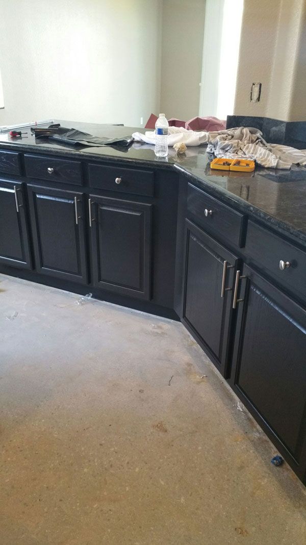 A kitchen with black cabinets and granite counter tops.