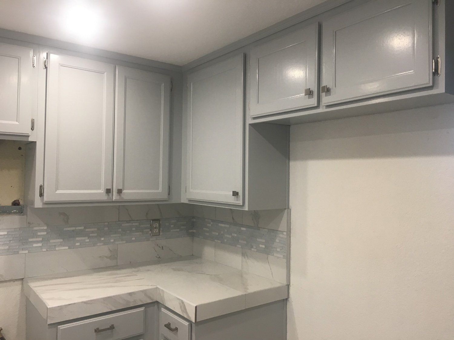 A kitchen with white cabinets and a white counter top.