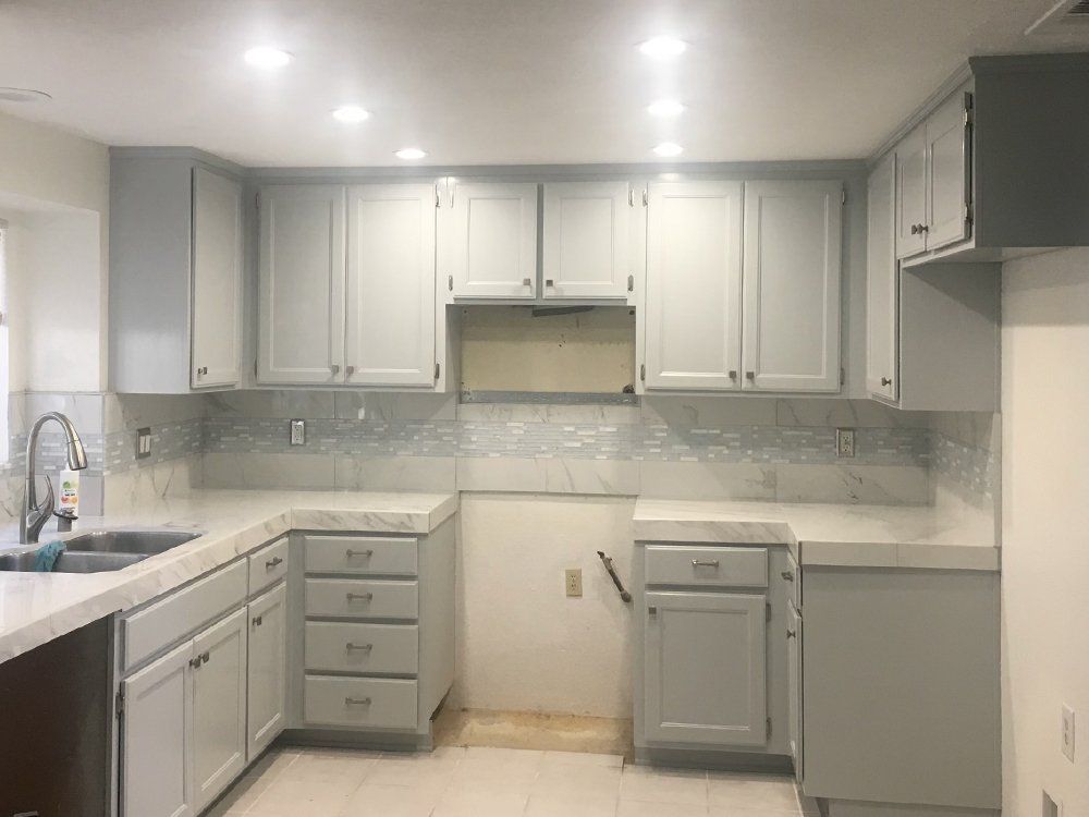 A kitchen with white cabinets, a sink, and a stove.
