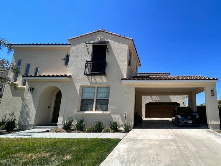 A white house with a car parked in front of it.