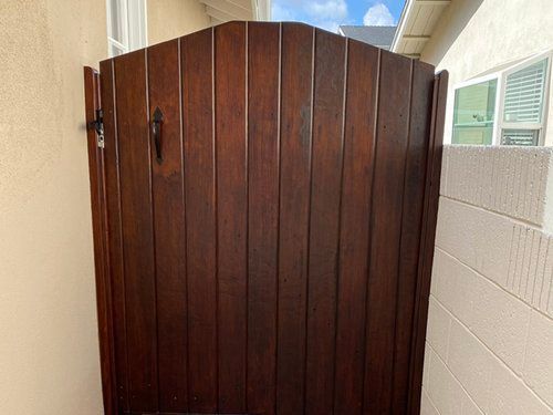 A wooden gate is sitting on the side of a house.