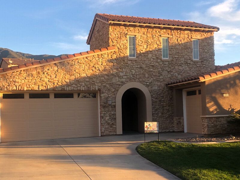 A large stone house with a For Sale sign in front of it.