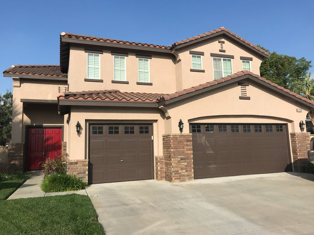 A large house with three garage doors and a red door.