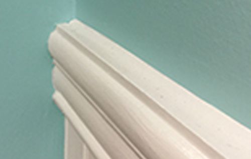 A close up of a white molding on a blue wall.