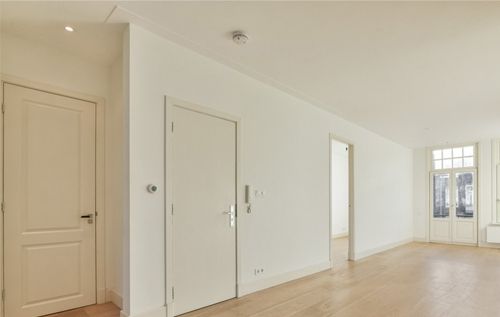 An empty room with white walls and wooden floors.