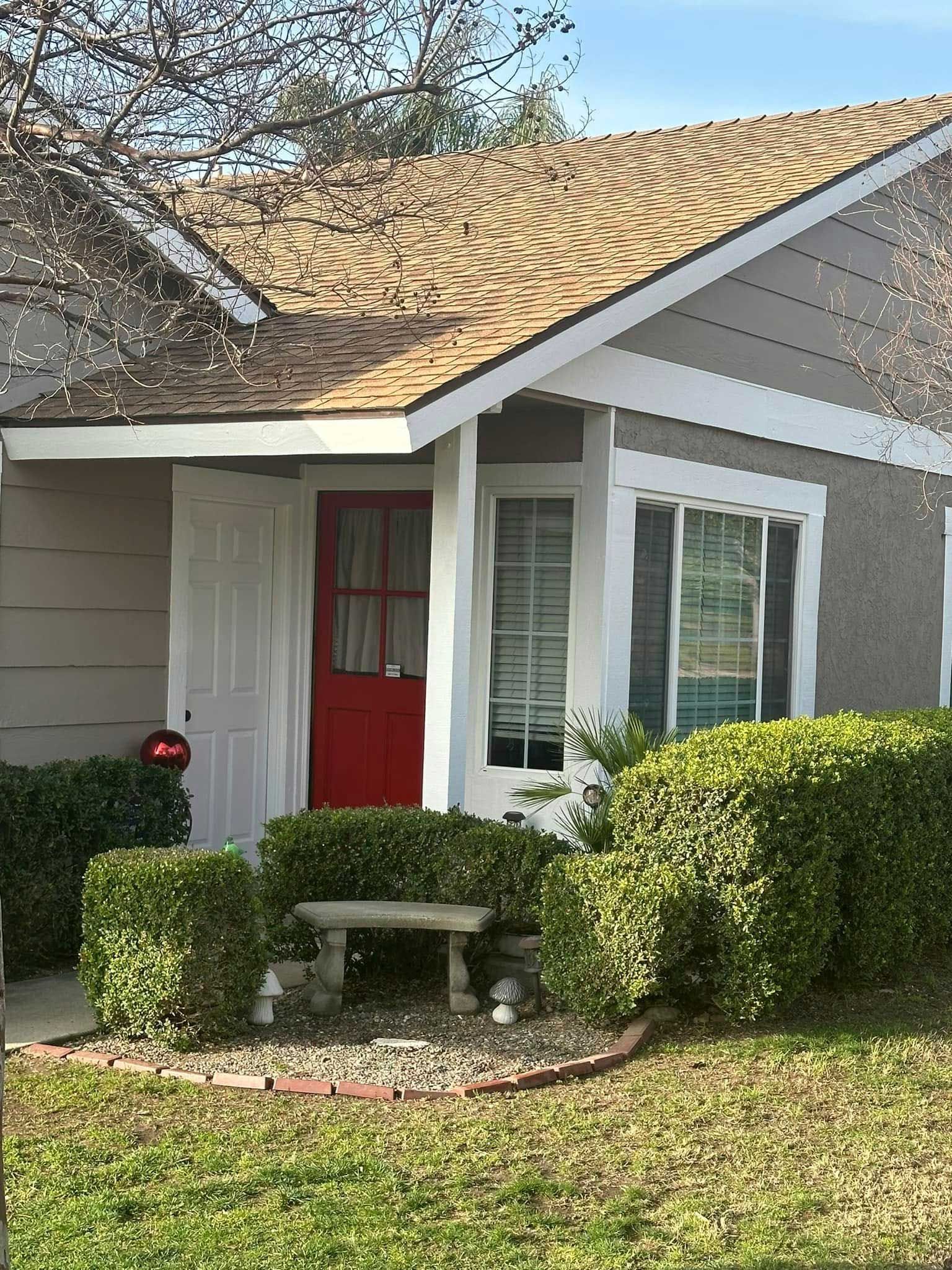 A small house with a red door and a bench in front of it.