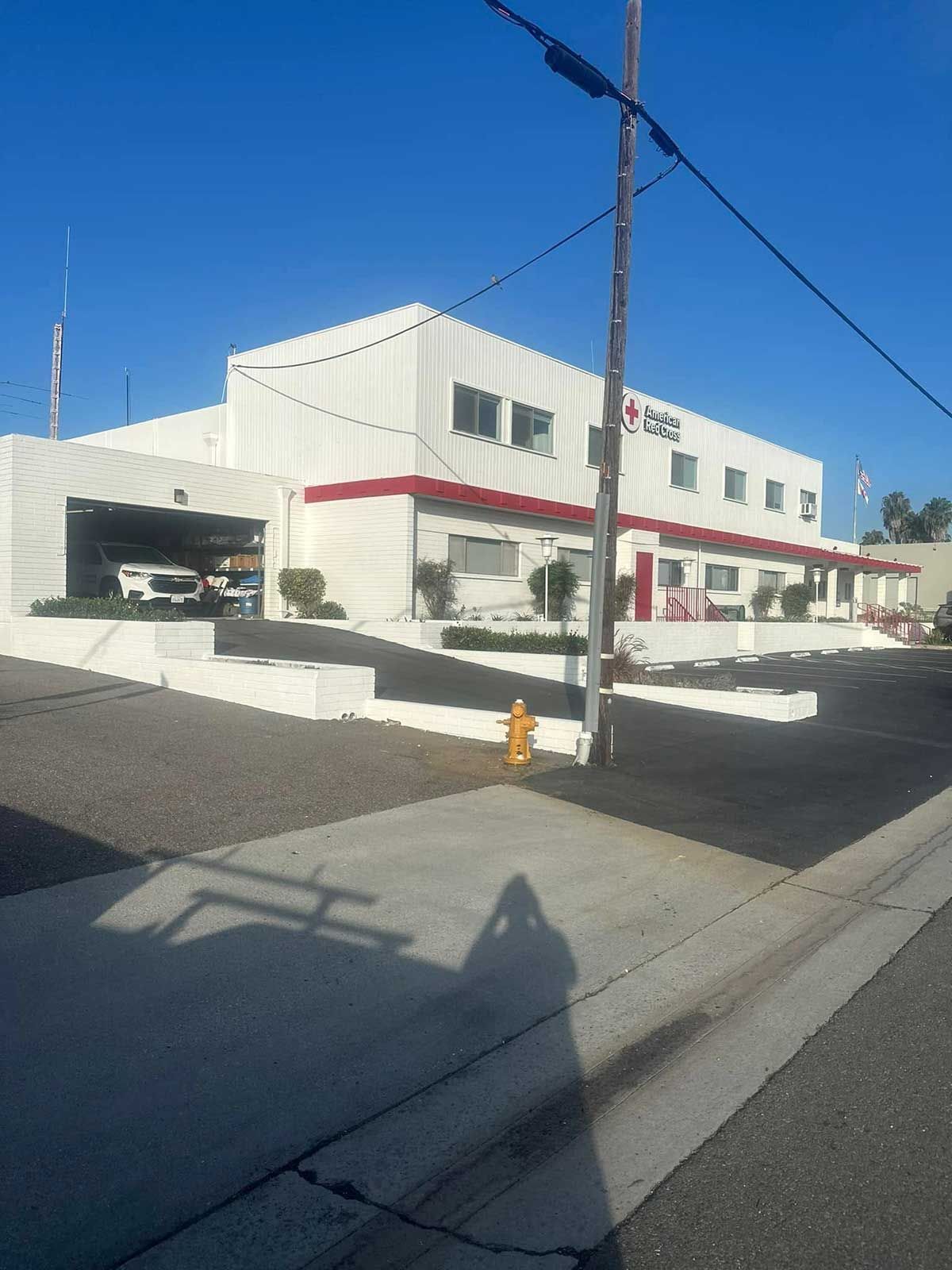 A white building with a red roof and a fire hydrant in front of it.