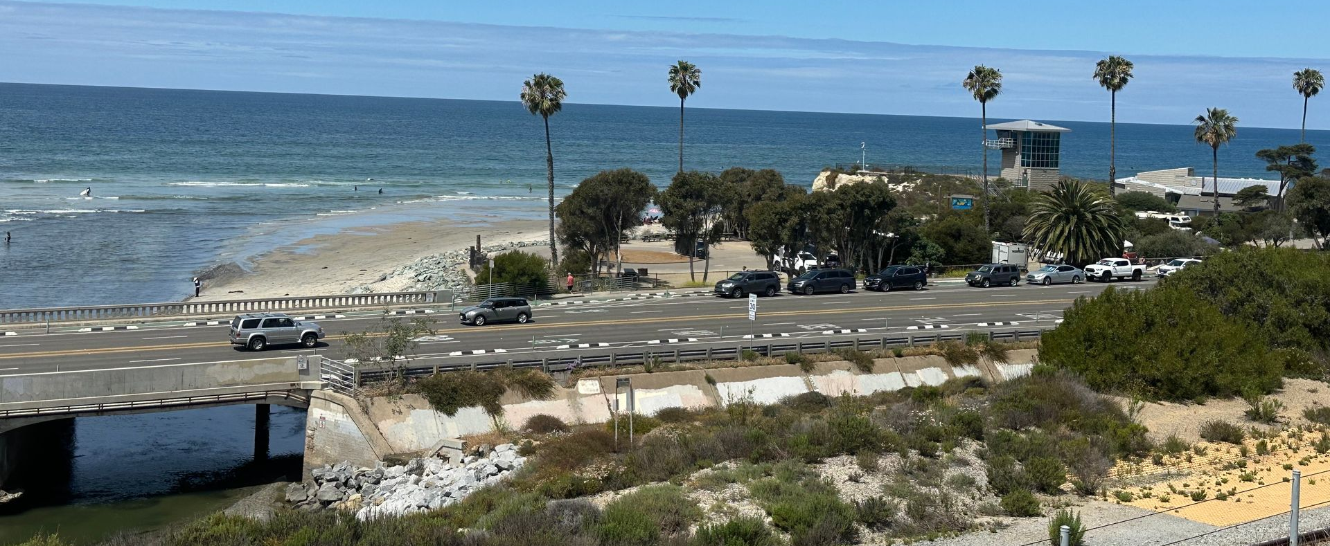 Lifeguard tower overlooking Cardiff State Beach in Encinitas, California, with sandy shoreline, rolling Pacific Ocean waves, and coastal scenery under a clear Southern California sky.