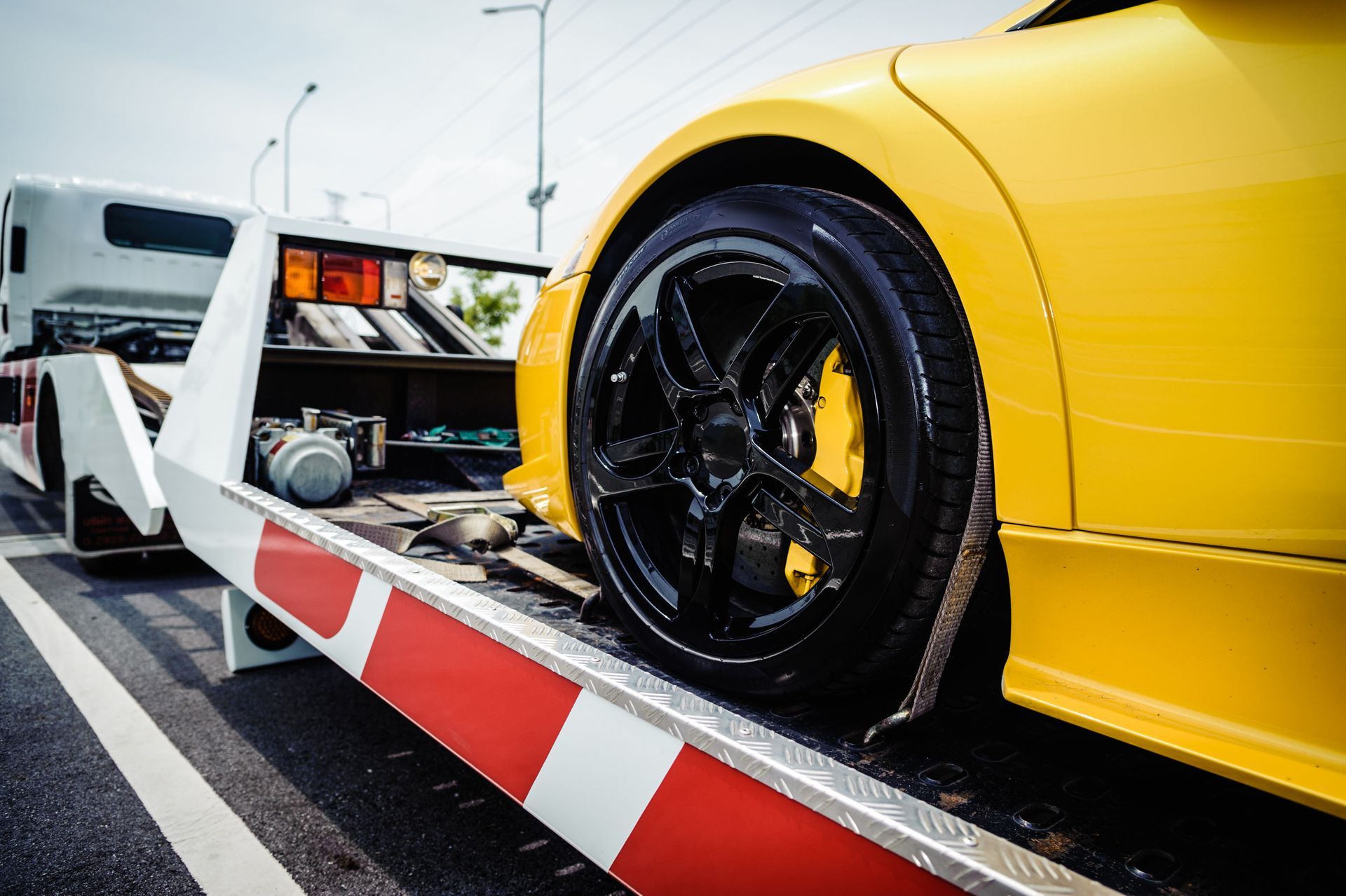 Yellow sports car being loaded onto a tow truck on a road