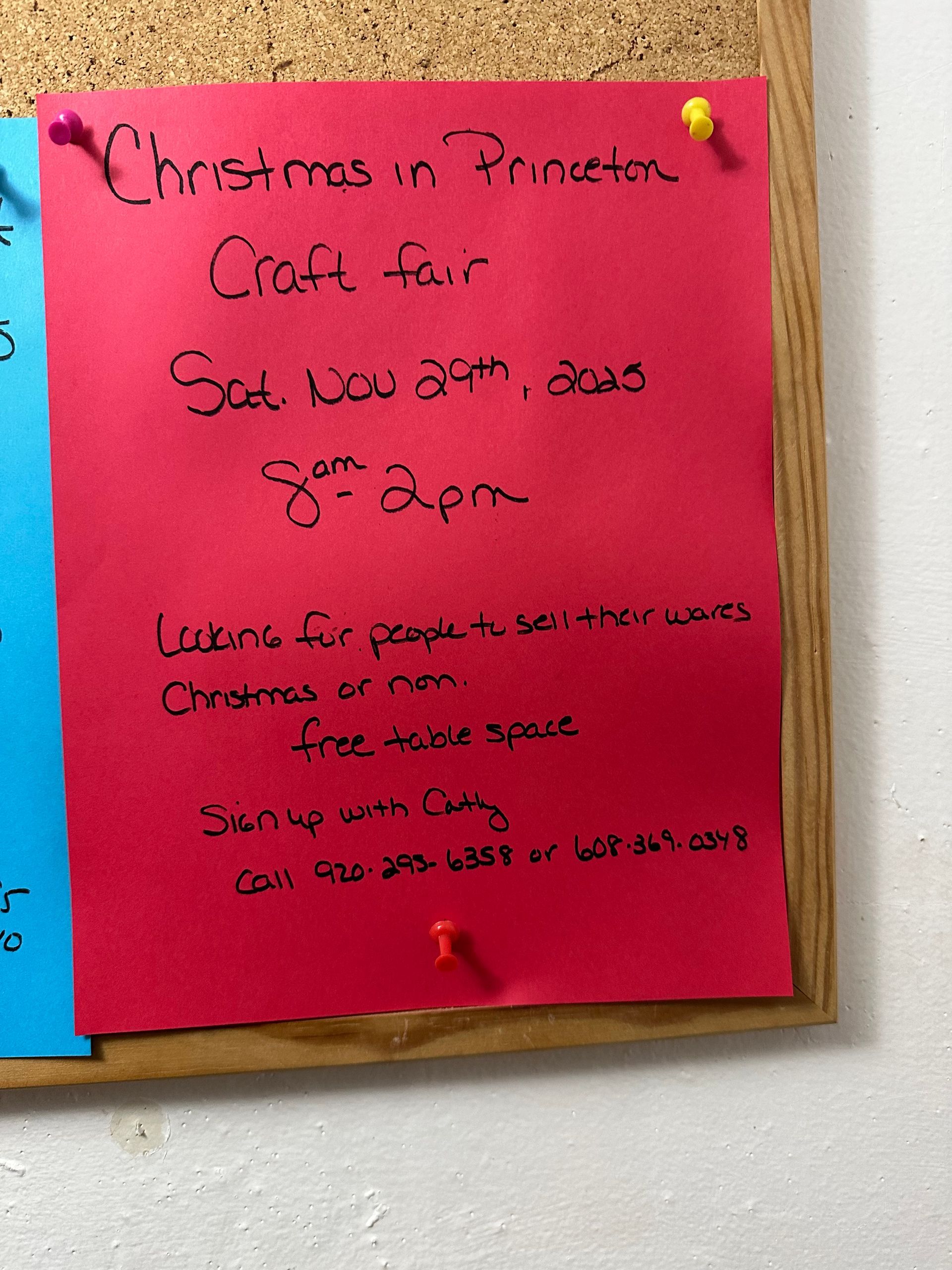 Red paper on a bulletin board advertises a Christmas craft fair in Princeton, Saturday, November 29th, 8 am-2 pm. Free vendor space available.