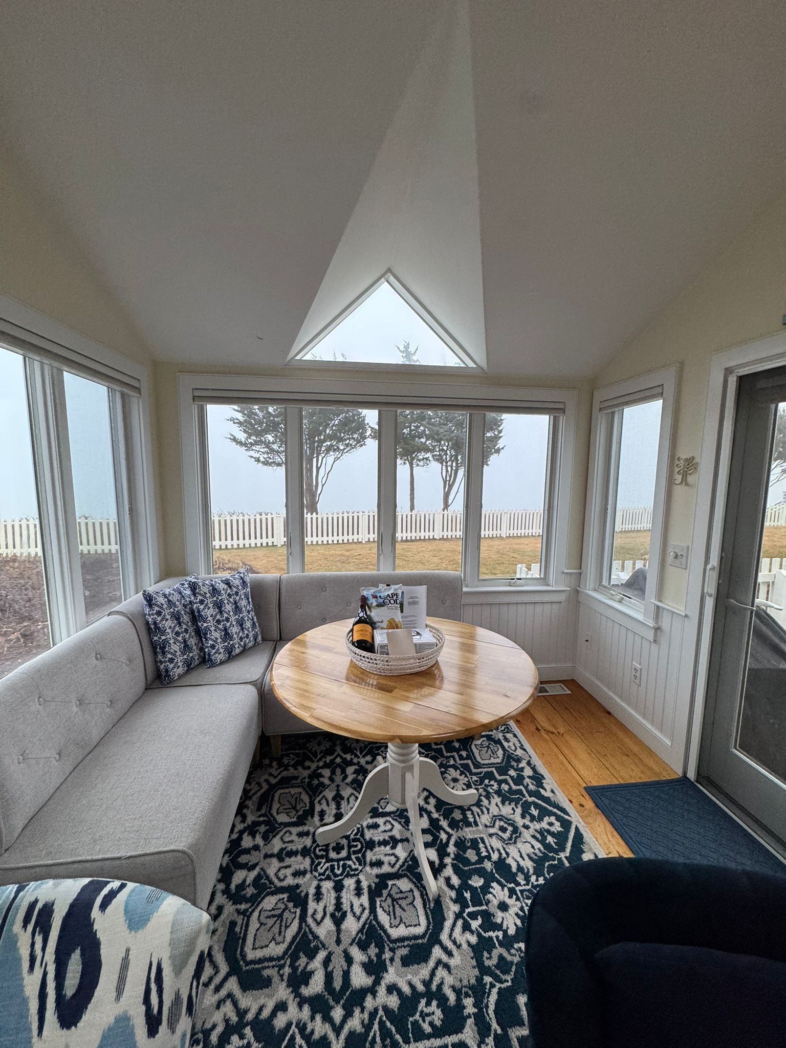 A living room with a couch, table, chairs and lots of windows