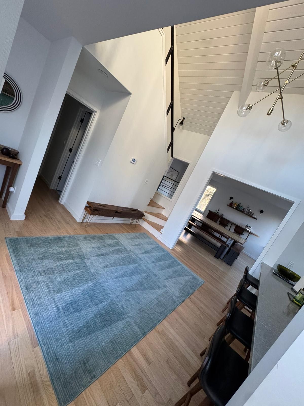 A living room with a blue rug and stairs