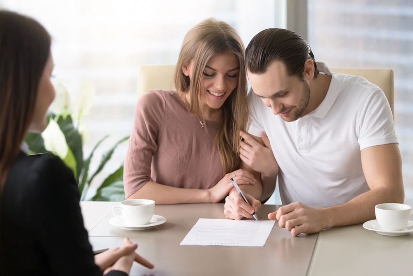 A man and a woman are sitting at a table signing a document.