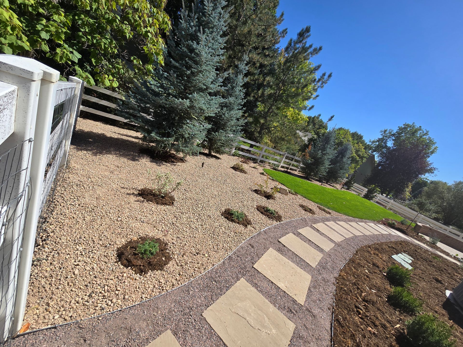 A walkway in a garden with a fence in the background