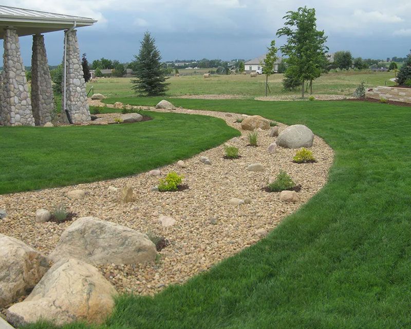 A lush green lawn with rocks and shrubs