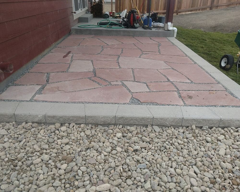 A brick walkway is surrounded by gravel in front of a house