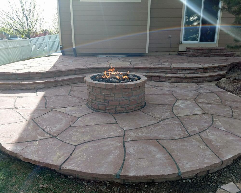 A fire pit is sitting on top of a patio next to a house.