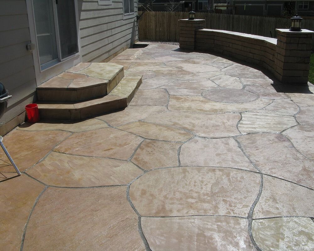 A stone patio with stairs and a brick wall