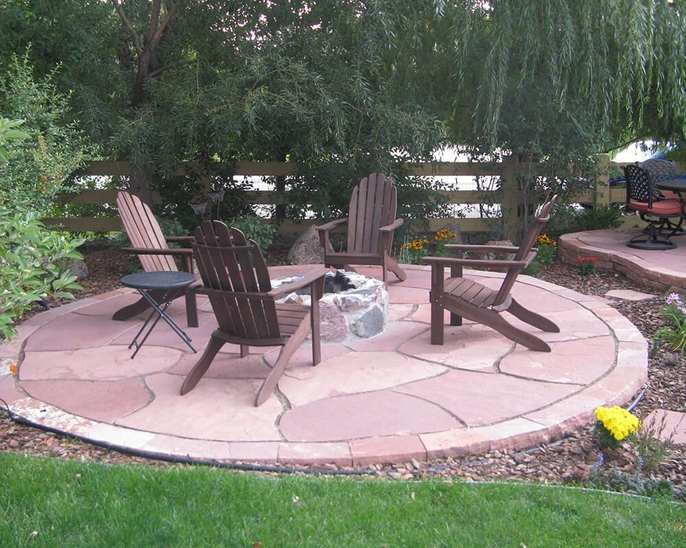 A group of chairs are sitting around a fire pit on a patio.
