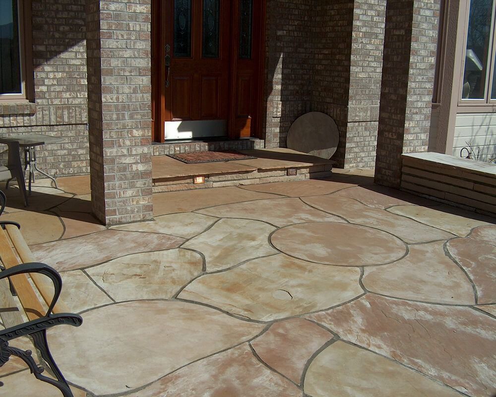 A patio with a bench and a table in front of a brick building