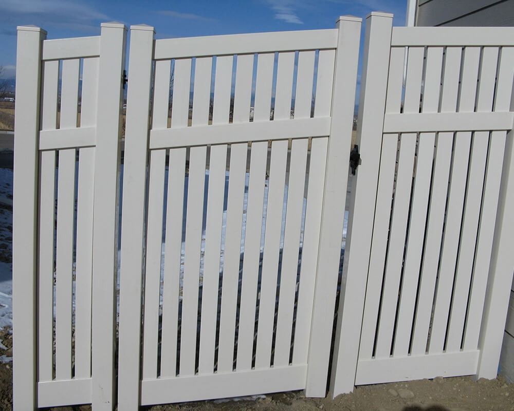 Three white fences are sitting next to each other on a dirt road.