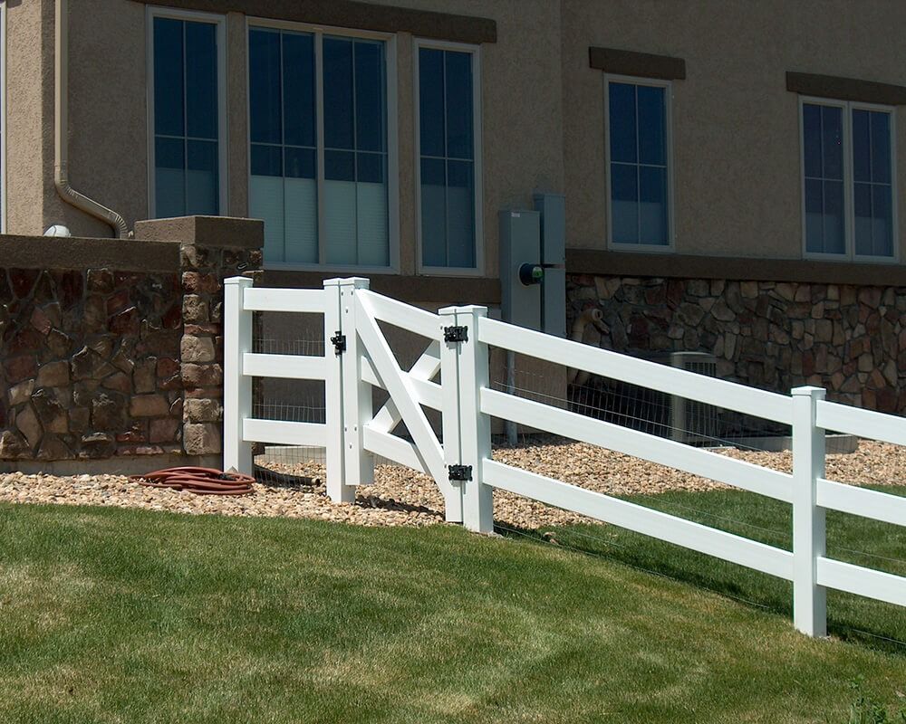 A white fence with a gate in front of a house