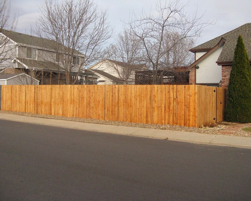 A wooden fence surrounds a house in a residential area