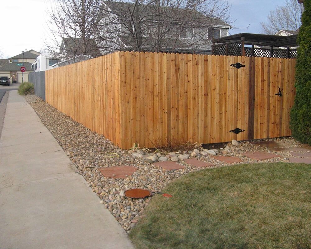 A wooden fence along a sidewalk next to a house