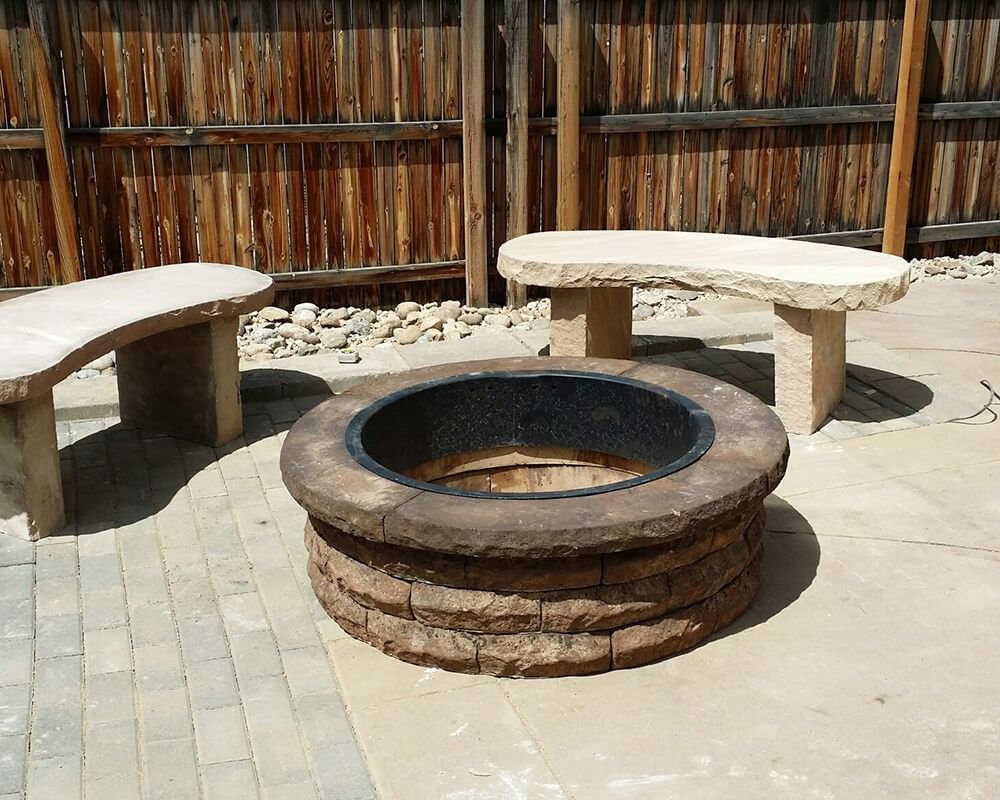 A fire pit surrounded by benches and a wooden fence