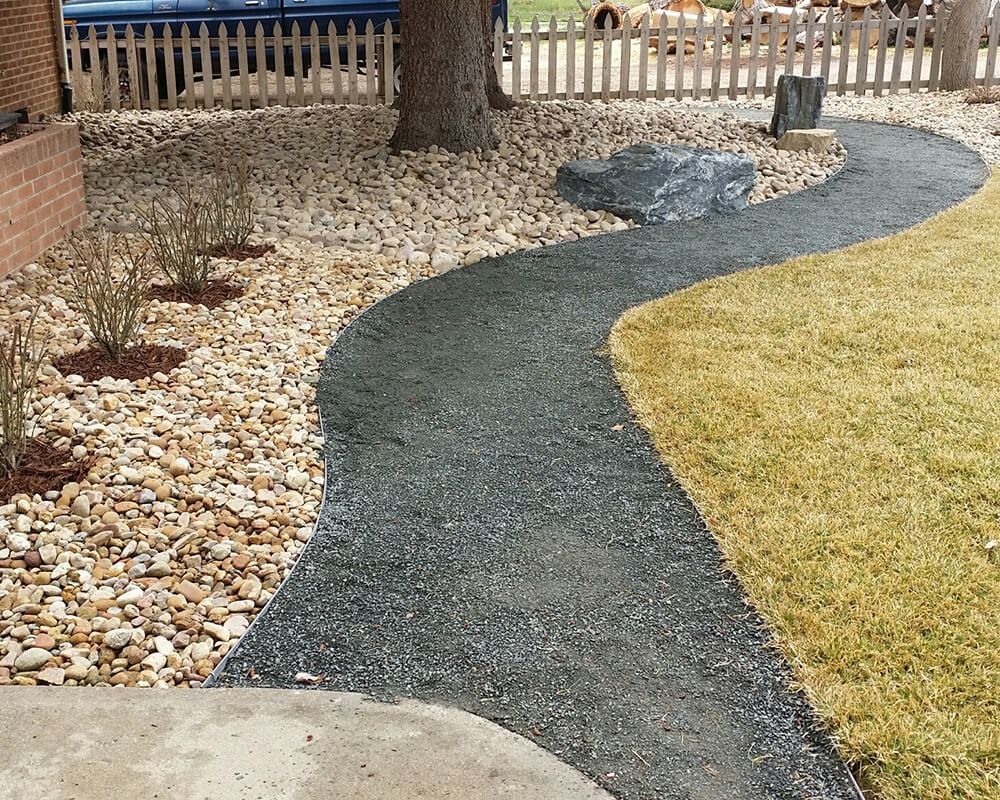 A walkway in a yard with a fence in the background