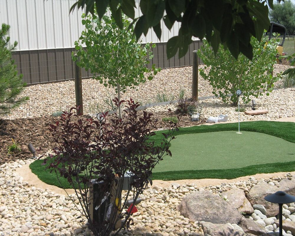 A putting green is surrounded by rocks and trees