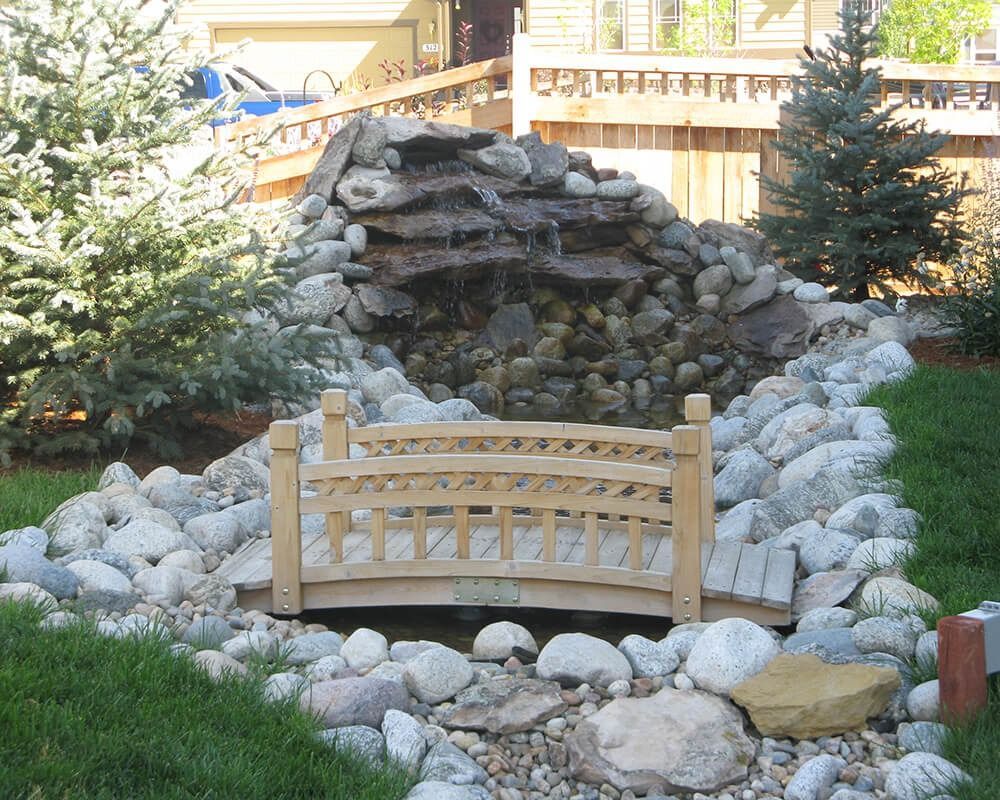 A small wooden bridge in front of a waterfall