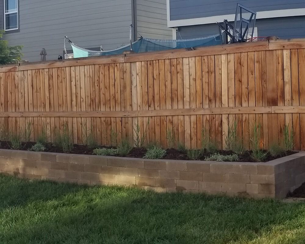 A wooden fence with a planter in front of it