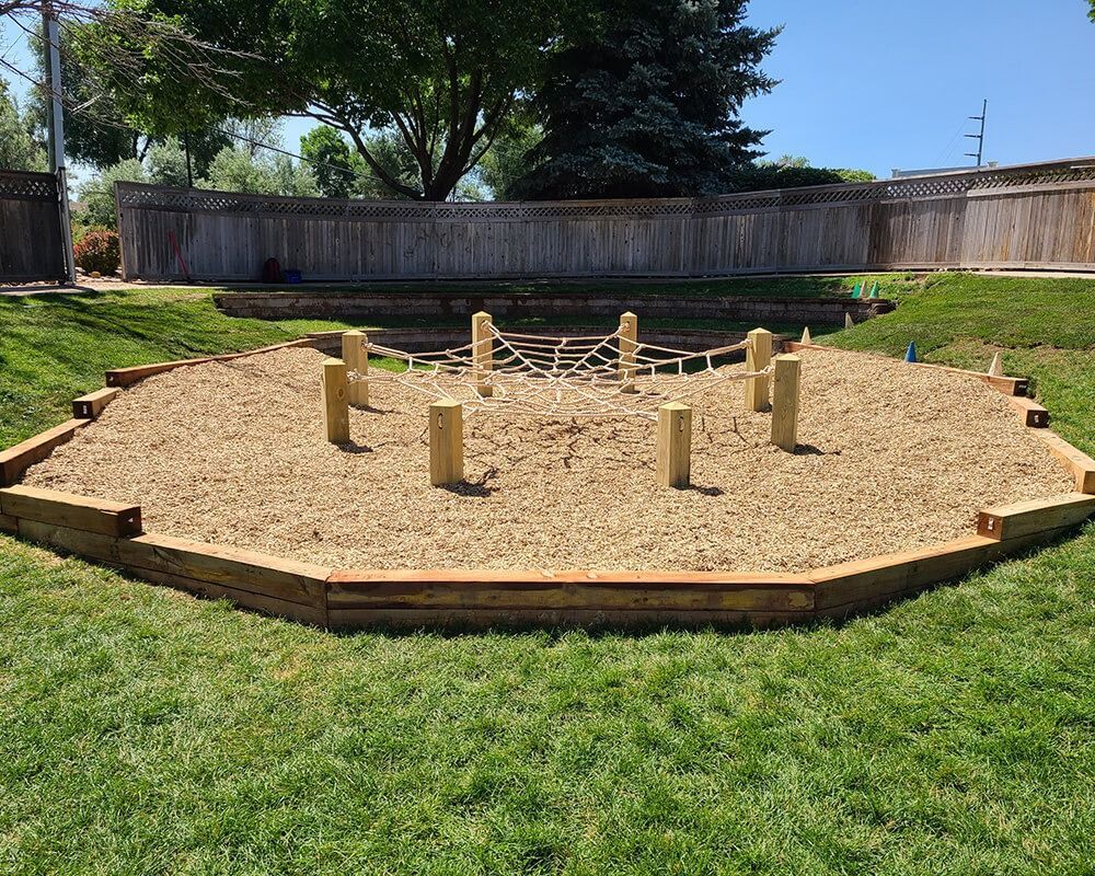 A sandbox with a ropes course in the middle of it.