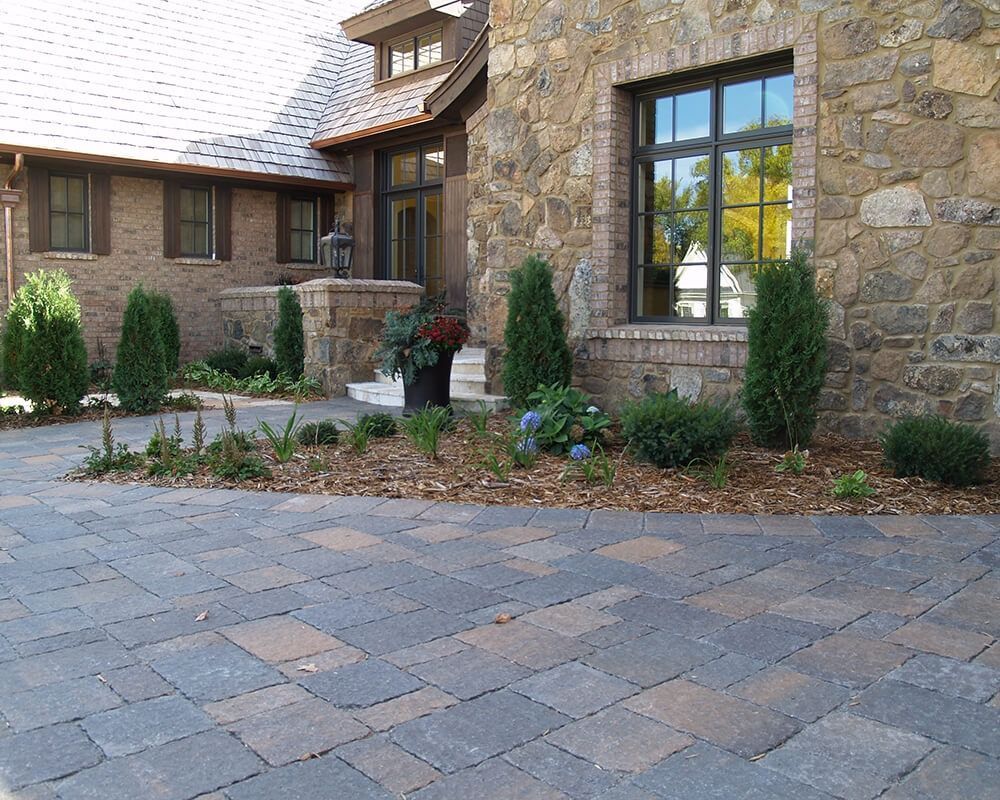 A stone house with a brick driveway in front of it