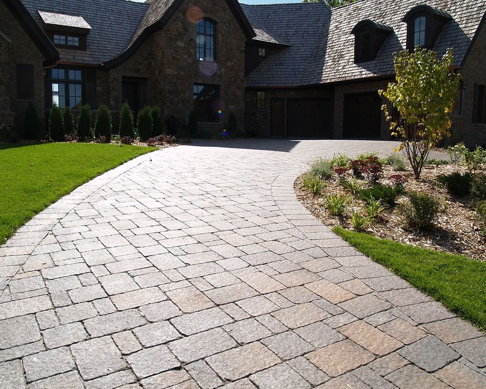 A brick driveway leading to a large house