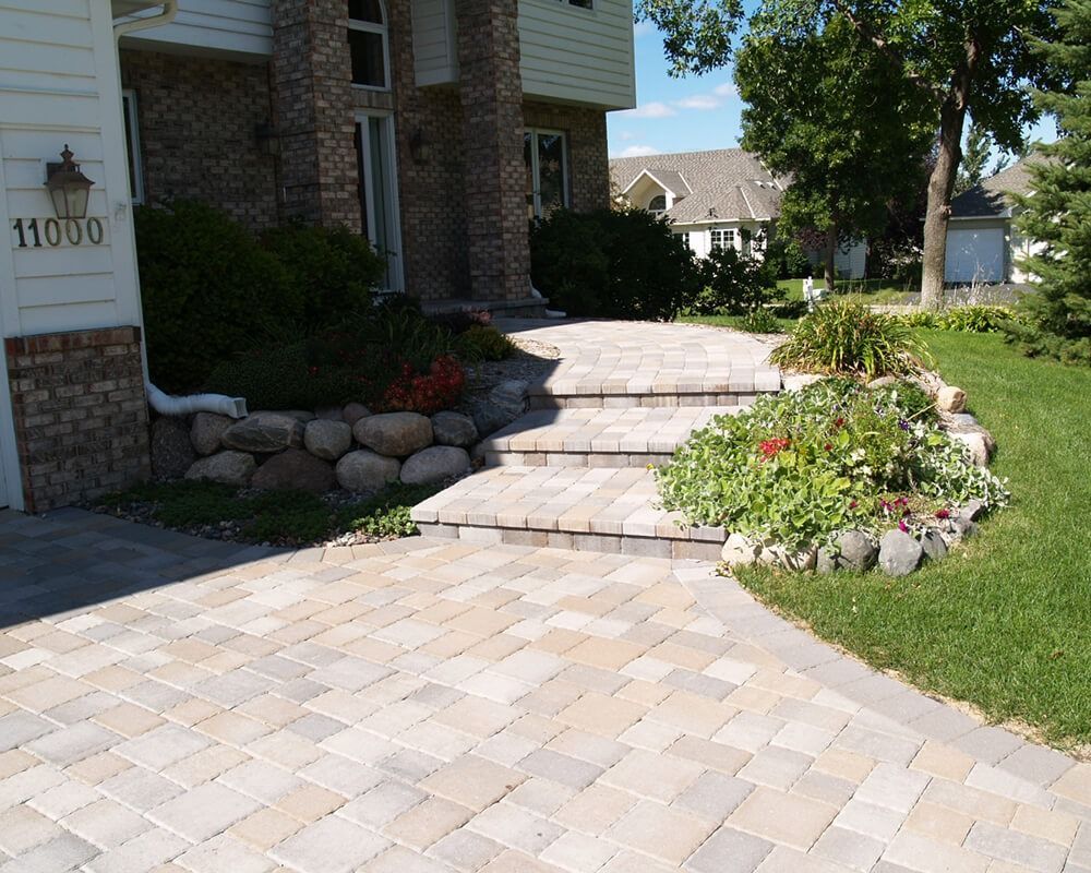 A brick walkway leading to a house with the number 1000 on the side