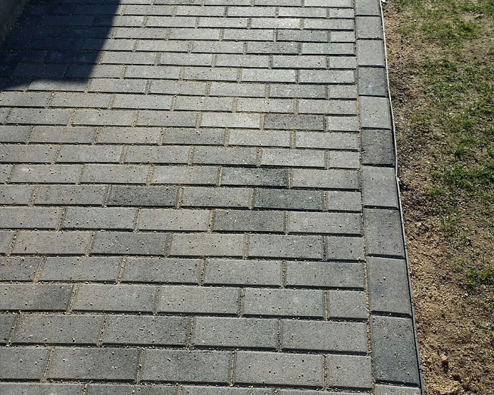 A brick walkway with grass in the background