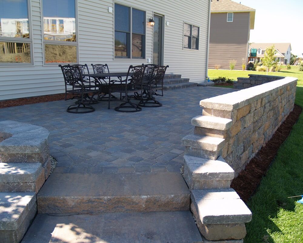 A patio with a table and chairs in front of a house