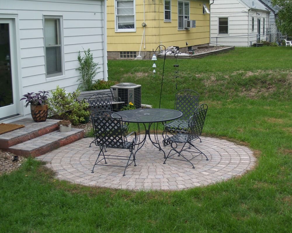 A patio with a table and chairs in front of a house